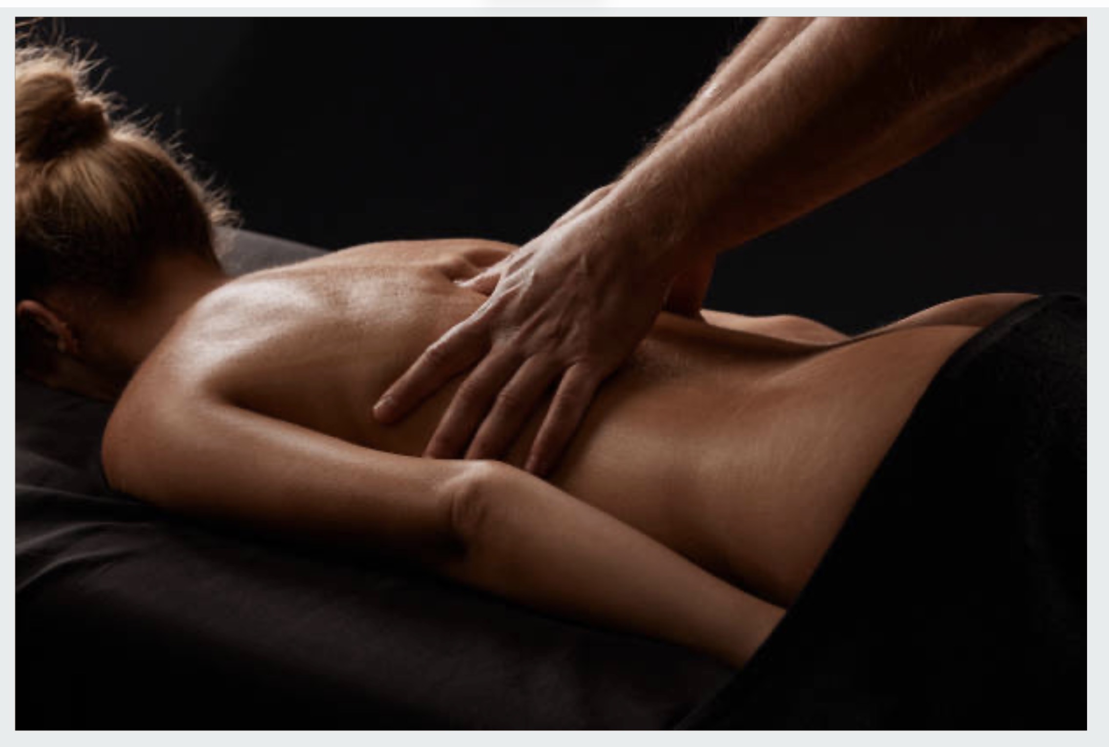 Woman receiving a back massage, with the therapist’s arms and hands visible